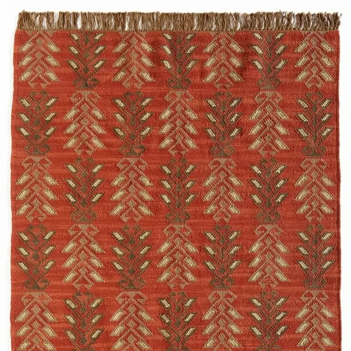 Coral flat-woven rug covered in cream and olive frond motifs, with natural fringe